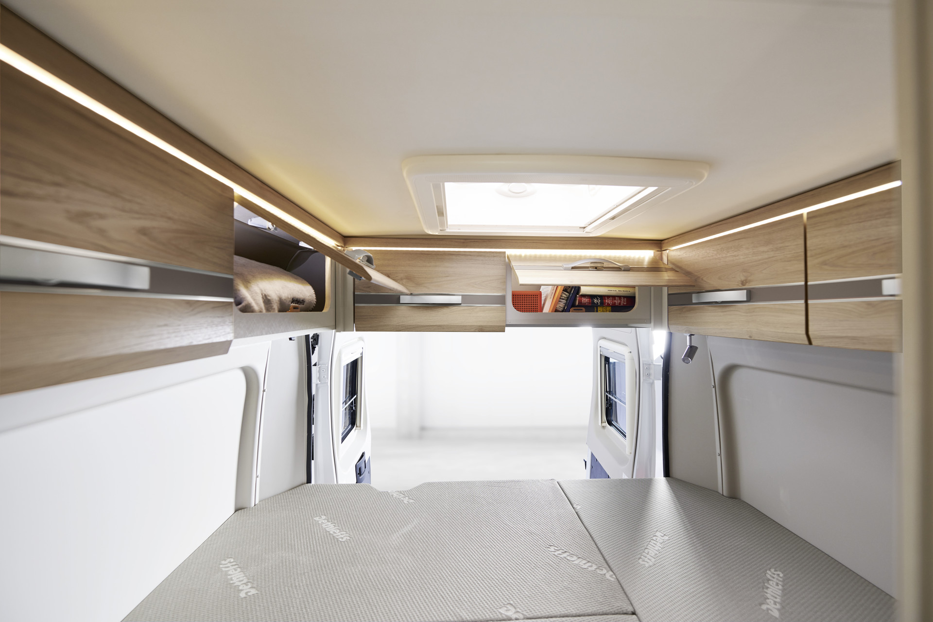 Les placards de pavillon de série au-dessus des portes arrière offrent un espace de rangement supplémentaire et bénéficient d’un éclairage indirect.